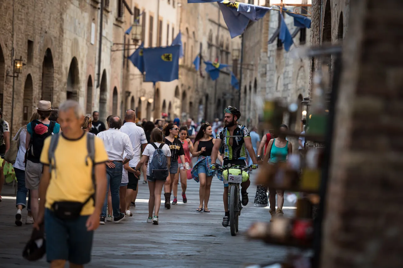Rider e passanti in una via di San Gimignano